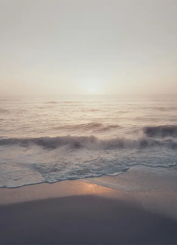 Gentle ocean waves at misty sunrise