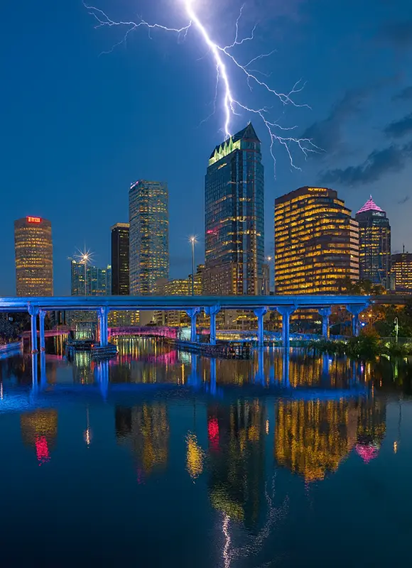 Lightning strike over Tampa skyline with reflections in water.