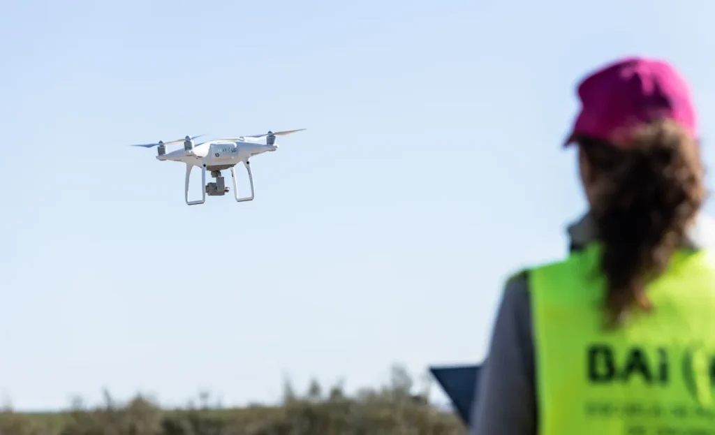 Drone flying in the sky with operator in the foreground.