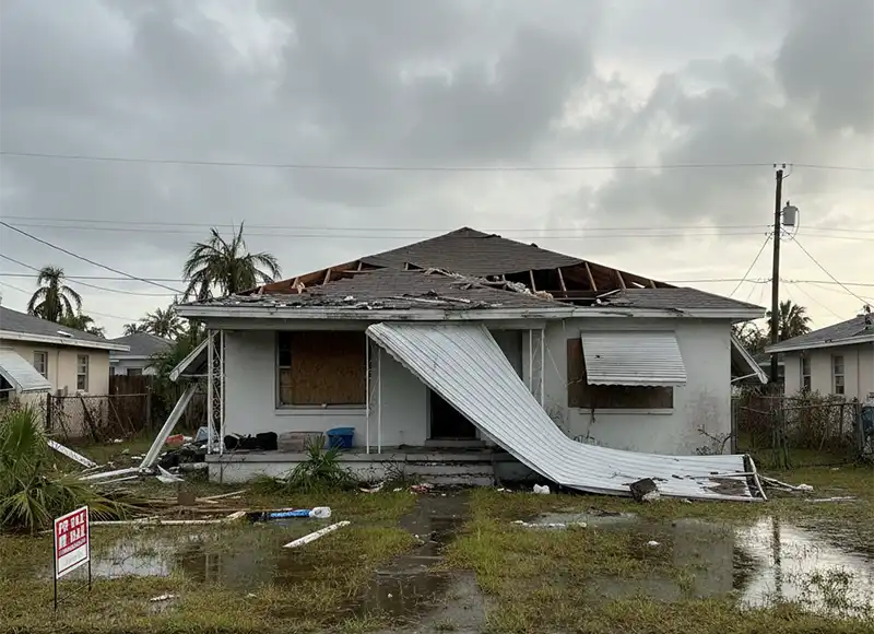 Hurricane winds peeling metal awning off damaged boarded-up Florida home