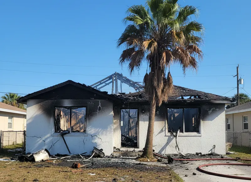 Severely fire-damaged Florida home with burned roof and charred walls