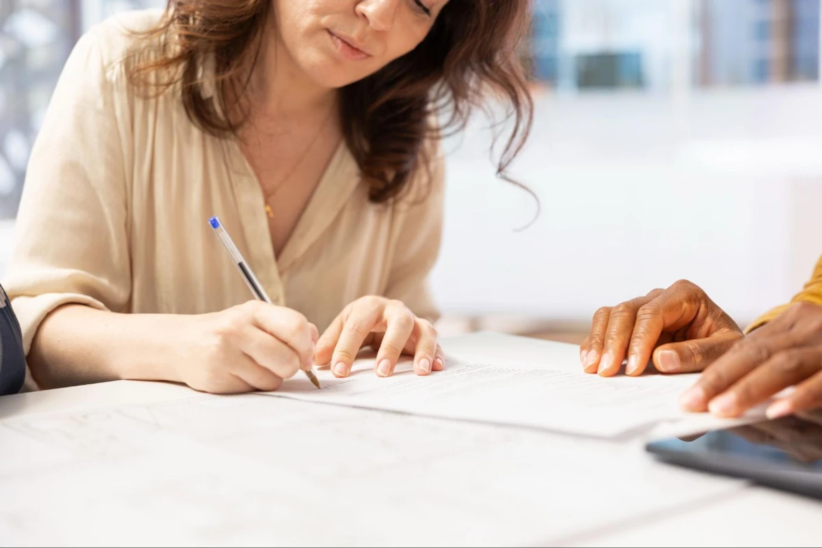 Woman signing paperwork during assisted consultation meeting